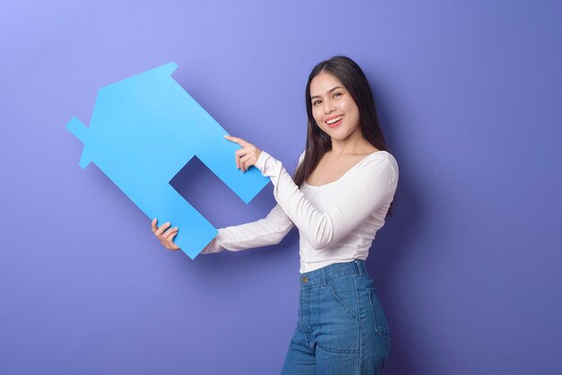 Portrait of beautiful woman is holding blue home on purple\
background