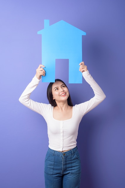 Portrait of beautiful woman  is holding blue  home on purple background