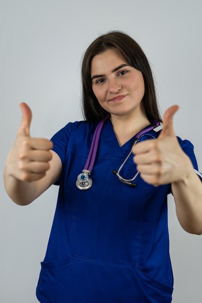 Portrait of beautiful woman medical student or doctor in blue uniform with stethoscope isolated on grey Medical concept healthcare