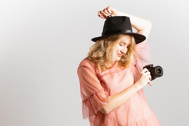 Ritratto di una bella donna fotografa con un cappello in posa con una macchina fotografica in mano in studio su sfondo bianco