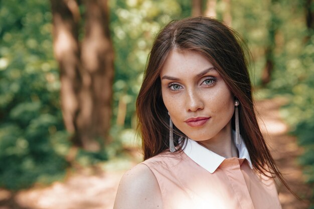 Portrait of beautiful woman posing on camera at green forest