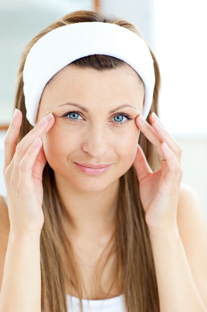 Photo portrait of a beautiful woman putting moisturizer on her face