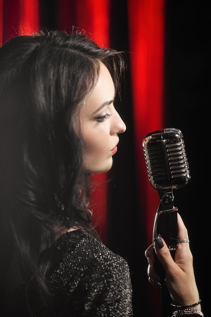 Portrait of beautiful woman singing in microphone