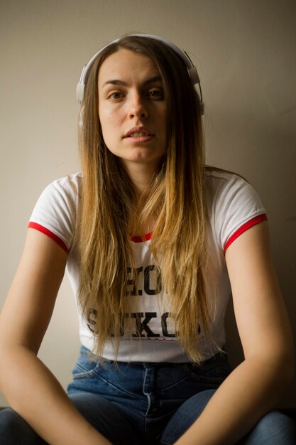 Photo portrait of beautiful woman sitting against wall