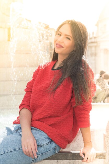 Photo portrait of beautiful woman sitting at fountain in city