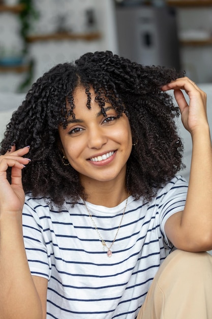 Ritratto di una bella donna sorridente a casa donna africana in casual guardando la fotocamera con spazio di copia ragazza allegra di razza mista che si rilassa a casa con una grande risata