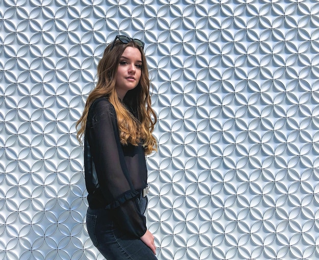 Foto ritratto di una bella donna in piedi contro un muro di mattoni