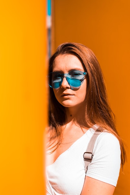 Portrait of beautiful woman standing against orange wall