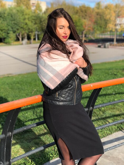 Portrait of beautiful woman standing by railing in park