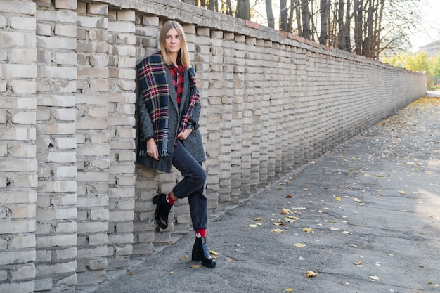 Portrait of a beautiful woman standing near a brick fence, going into the distance