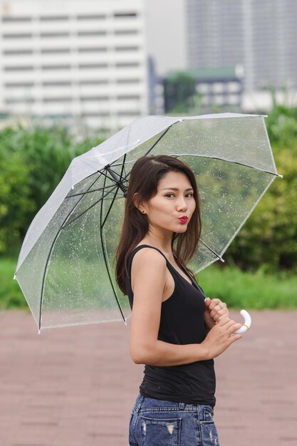 Portrait of beautiful woman standing on wet umbrella