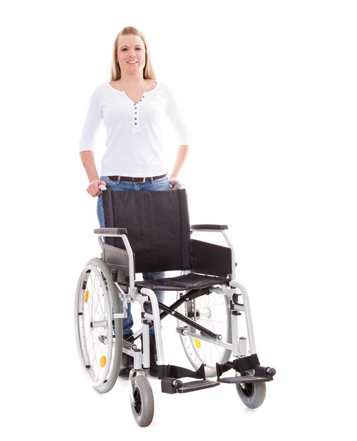 Foto ritratto di una bella donna in piedi con una sedia a rotelle su uno sfondo bianco