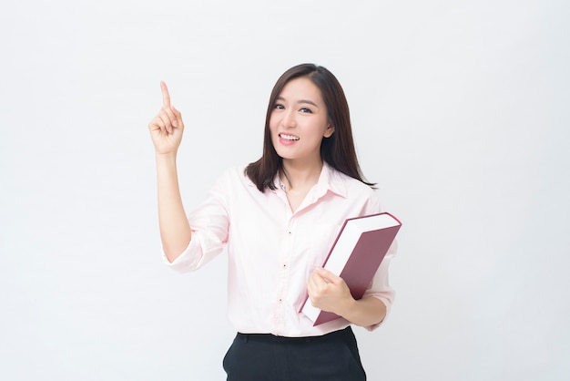 Portrait of beautiful woman student in pink shirt is holding a book isolated over white background studio