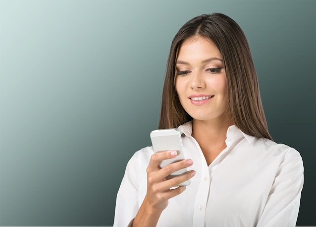 Portrait of a beautiful woman typing on the smart phone in a park with a green unfocused background