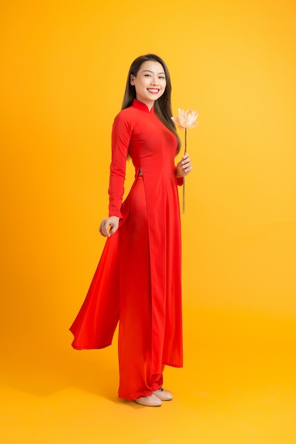 Portrait beautiful woman in vietnamese traditional costume holding pink lotus on yellow