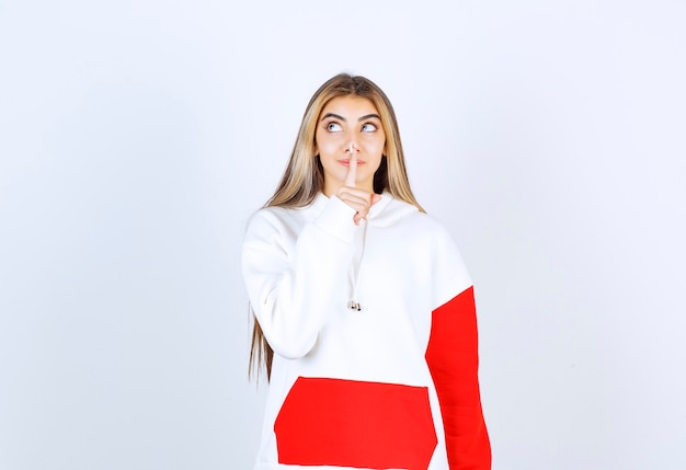 Portrait of a beautiful woman in warm hoodie standing and doing silent sign 