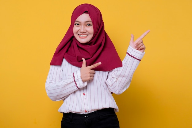 Portrait of beautiful woman wearing hijab pointing up left side and smile, cheerful expression