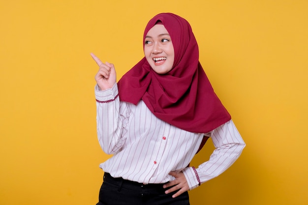 Portrait of beautiful woman wearing hijab pointing up right side and smile, cheerful expression