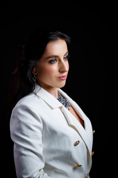 Portrait of a beautiful woman in a white classic jacket on a black background