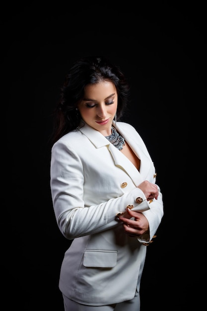 Portrait of a beautiful woman in a white classic jacket on a black background