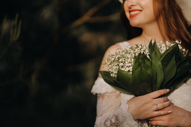 Portrait of a beautiful woman in a white dress and a hat with lilies of the valley A girl in nature Spring flowers