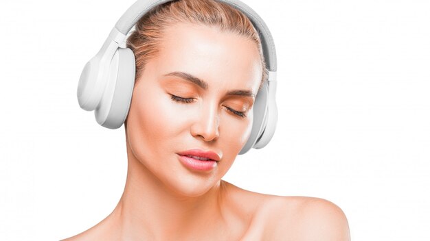 Portrait of a beautiful woman in white headphones listening to the music with closed eyes.