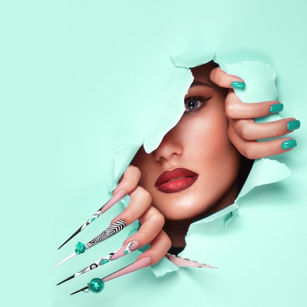 Portrait of a beautiful woman with art make up in glamorous style creative long nails on a blue background Design manicure Beauty face