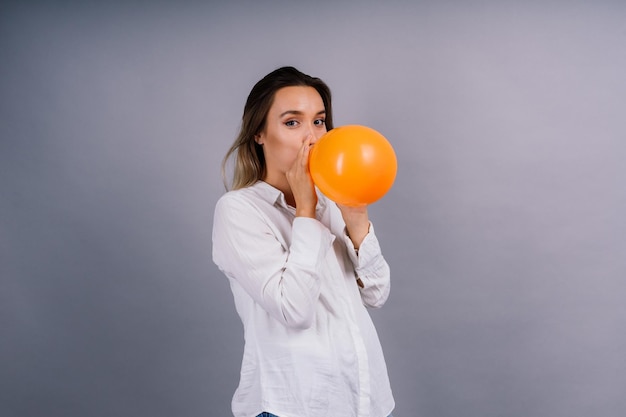 Ritratto di una bella donna con un palloncino in mano su uno sfondo grigio in studio