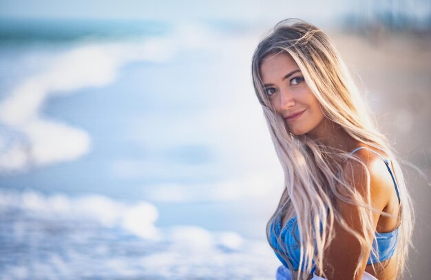 Portrait of a beautiful woman with blond hair in a blue swimsuit and white shirt