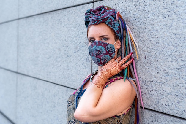 Portrait of beautiful woman with blue eyes with hand decorated with henna tattoo the new normal concept person wearing a fashionable protective mask