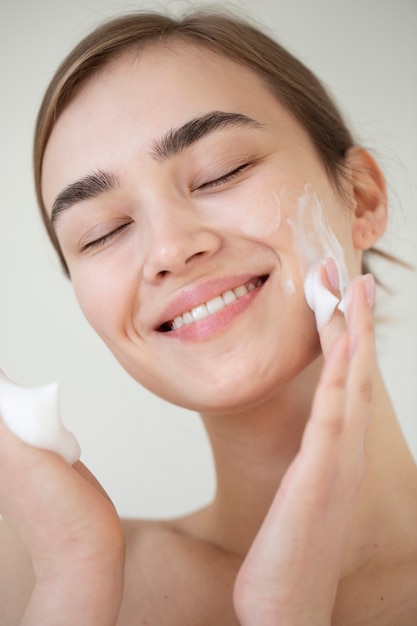 Portrait of beautiful woman with clear skin washing face with foam cleanser