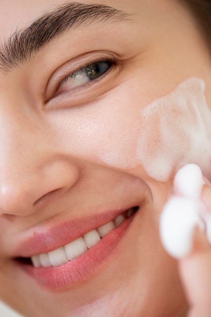 Photo portrait of beautiful woman with clear skin washing face with foam cleanser