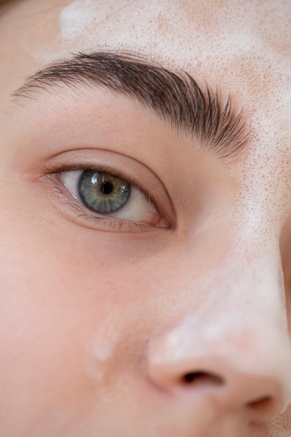 Photo portrait of beautiful woman with clear skin washing face with foam cleanser