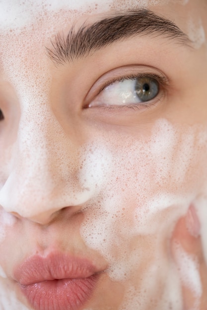 Photo portrait of beautiful woman with clear skin washing face with foam cleanser