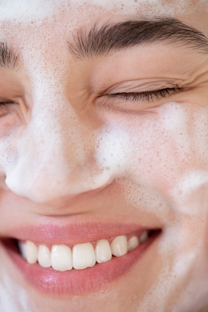 Photo portrait of beautiful woman with clear skin washing face with foam cleanser