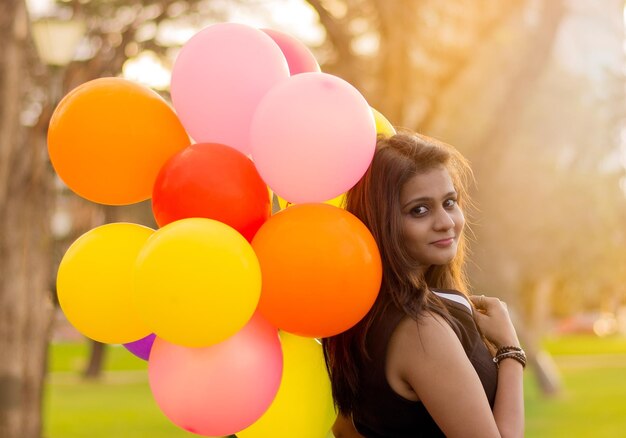 Portrait of beautiful woman with colorful balloons at park