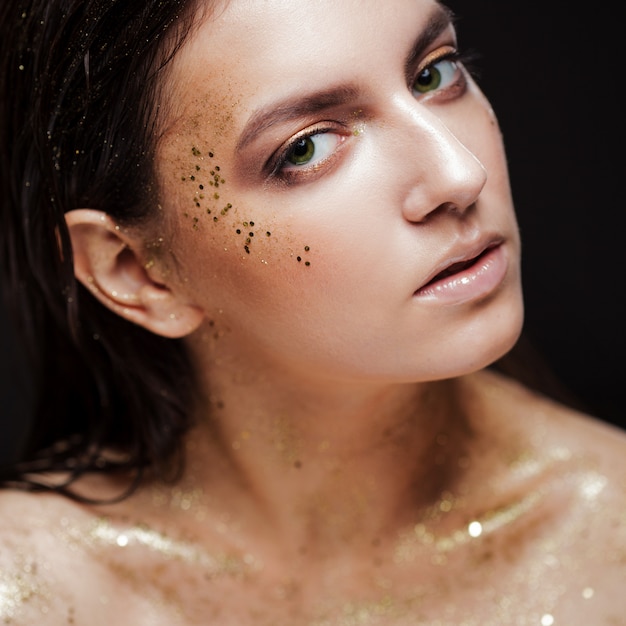 Portrait of a beautiful woman with creative gold make up