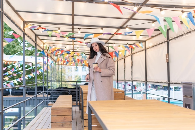 Portrait of a beautiful woman with a cup of coffee on the veranda in a cafe