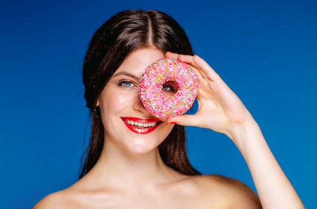 Portrait of beautiful woman with donut isolated on blue background