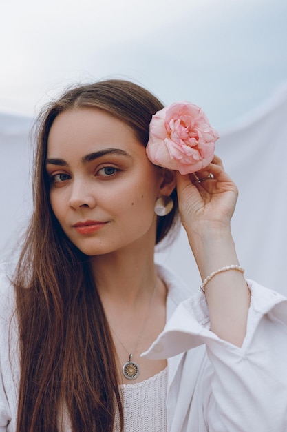 Portrait of beautiful woman with flower in hair looking at camera on white background