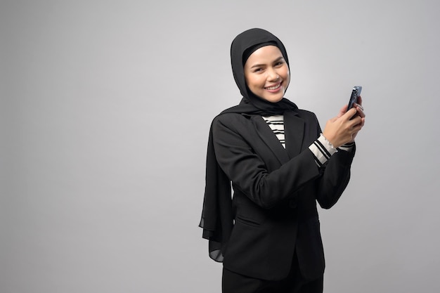 Portrait of beautiful woman with hijab using cellphone on white background