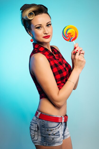 Portrait of beautiful woman with lollipop, dressed in pin-up style