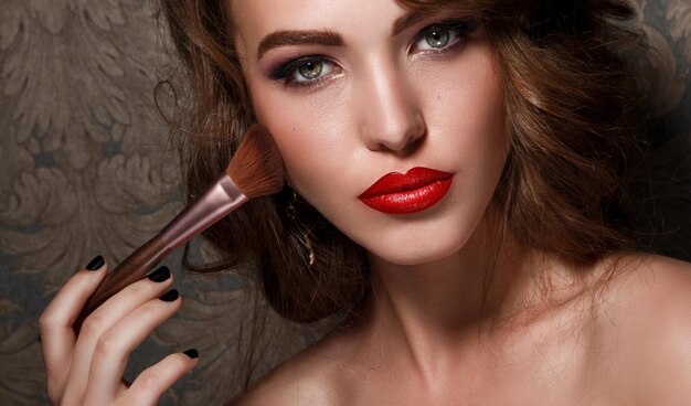 Photo portrait of beautiful woman with makeup brush