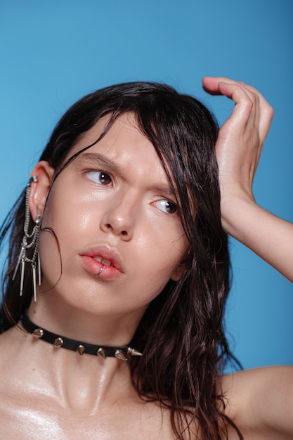 Portrait of beautiful woman with piercings and other accessories on blue