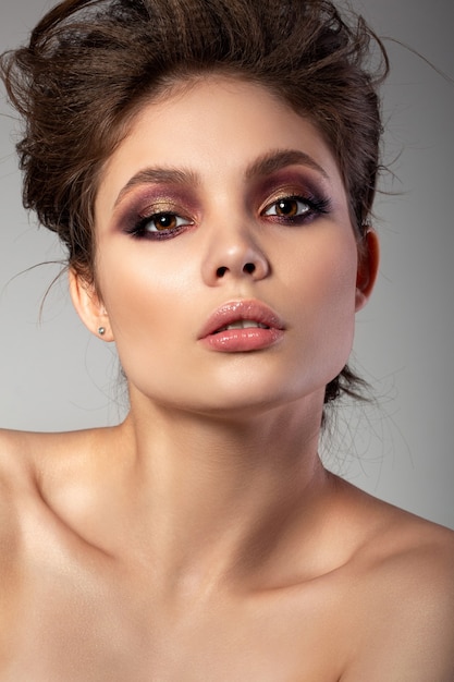 Portrait of beautiful woman with romantic red and gold smokey eyes makeup