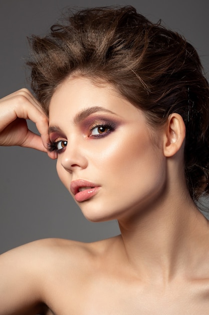 Ritratto di bella donna con trucco smokey eyes rosso e oro romantico