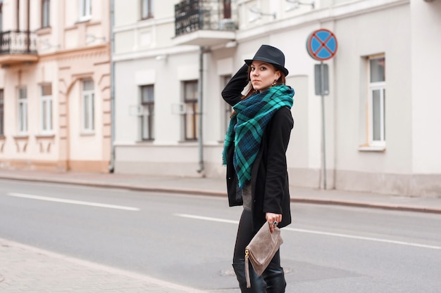 Портрет красивой женщины с шарфом и шляпой у дороги.