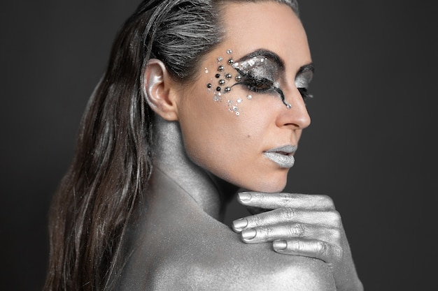 Photo portrait of a beautiful woman with silver paint on her skin and hair.