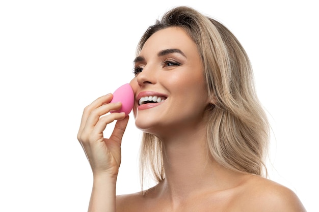 Portrait of beautiful woman with a smooth skin holding makeup sponge on white background