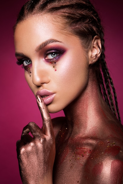 Photo portrait of beautiful woman with sparkles on her face.